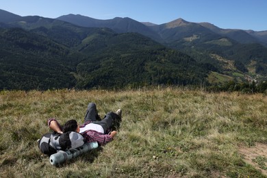 Tourist with backpack resting on ground in mountains