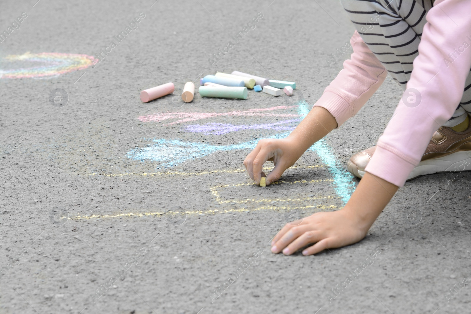 Photo of Little child drawing happy family with chalk on asphalt, closeup