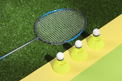 Photo of Shuttlecocks and racquet on green court combined with color paper background. Badminton equipment