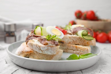 Photo of Delicious bruschettas with anchovies, tomato, cucumber, egg and cream cheese on white textured table, closeup