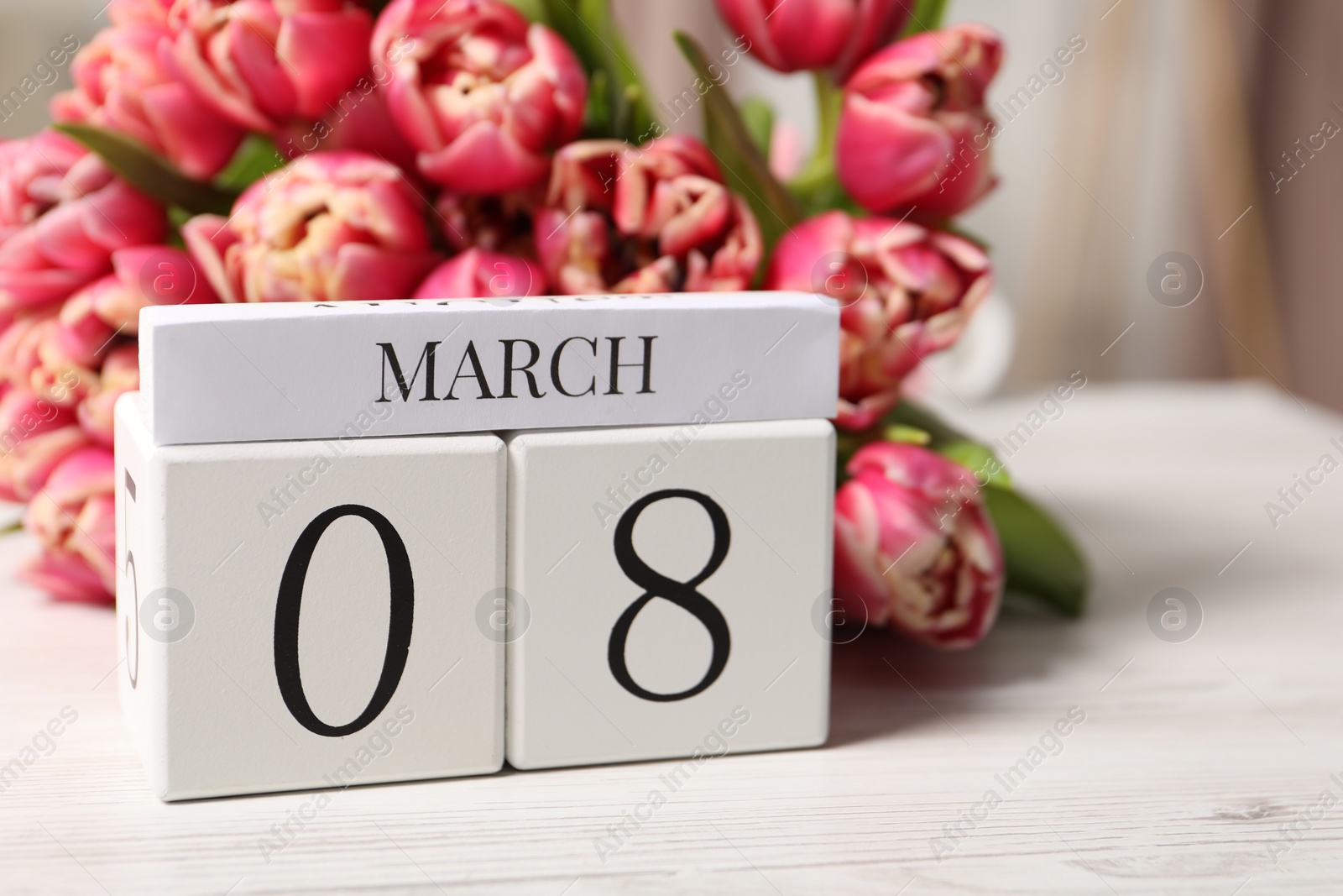 Photo of International Women's day - 8th of March. Block calendar and bouquet of beautiful tulips on white wooden table, closeup