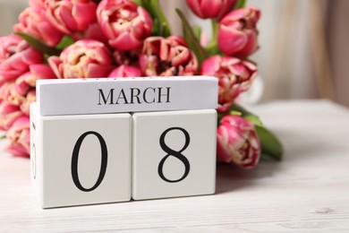 International Women's day - 8th of March. Block calendar and bouquet of beautiful tulips on white wooden table, closeup