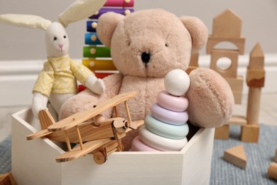 Photo of Set of different toys in box on floor, closeup
