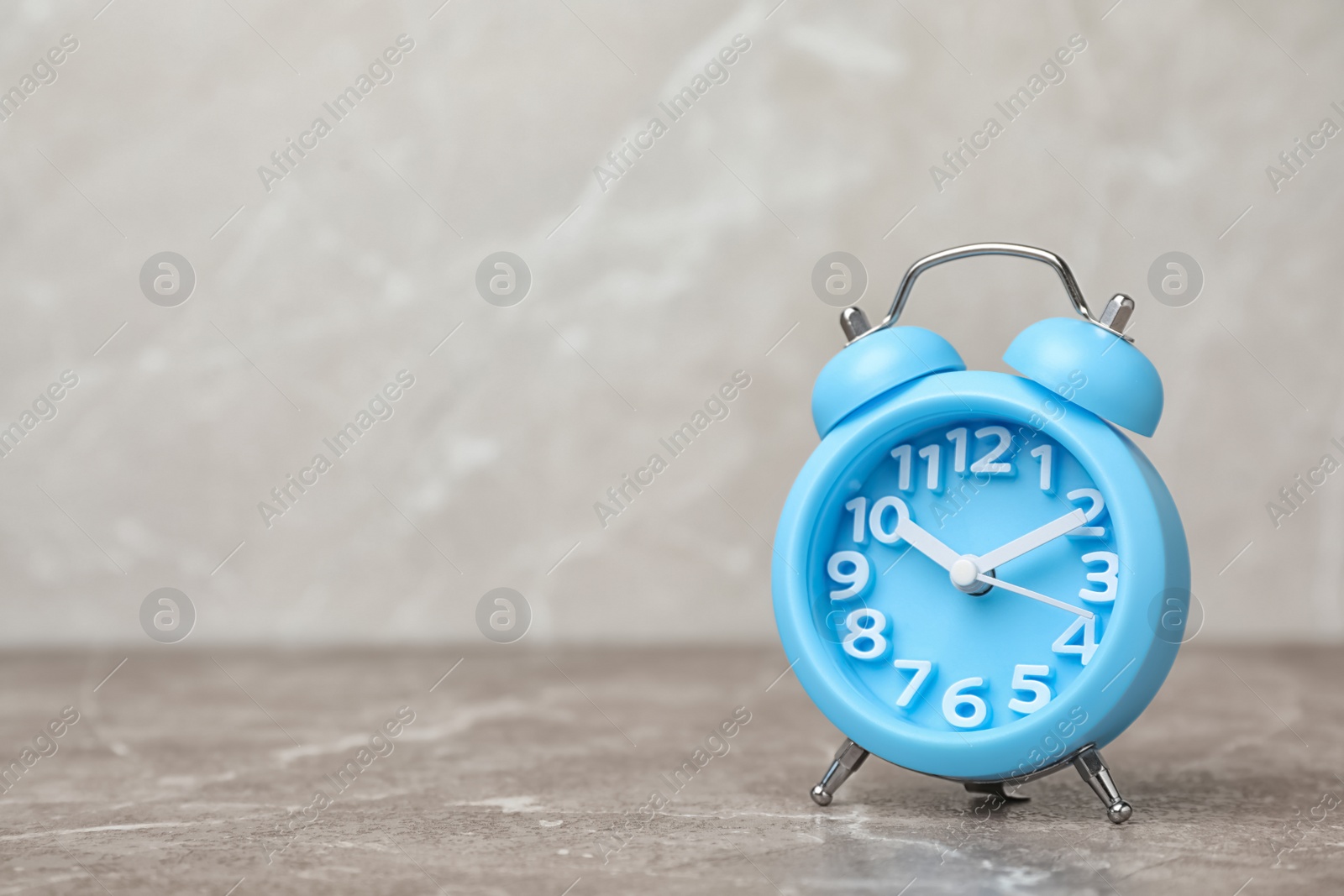 Photo of Alarm clock on table against grey background. Time concept