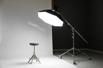 Photo of White photo background, stool and professional lighting equipment in modern studio