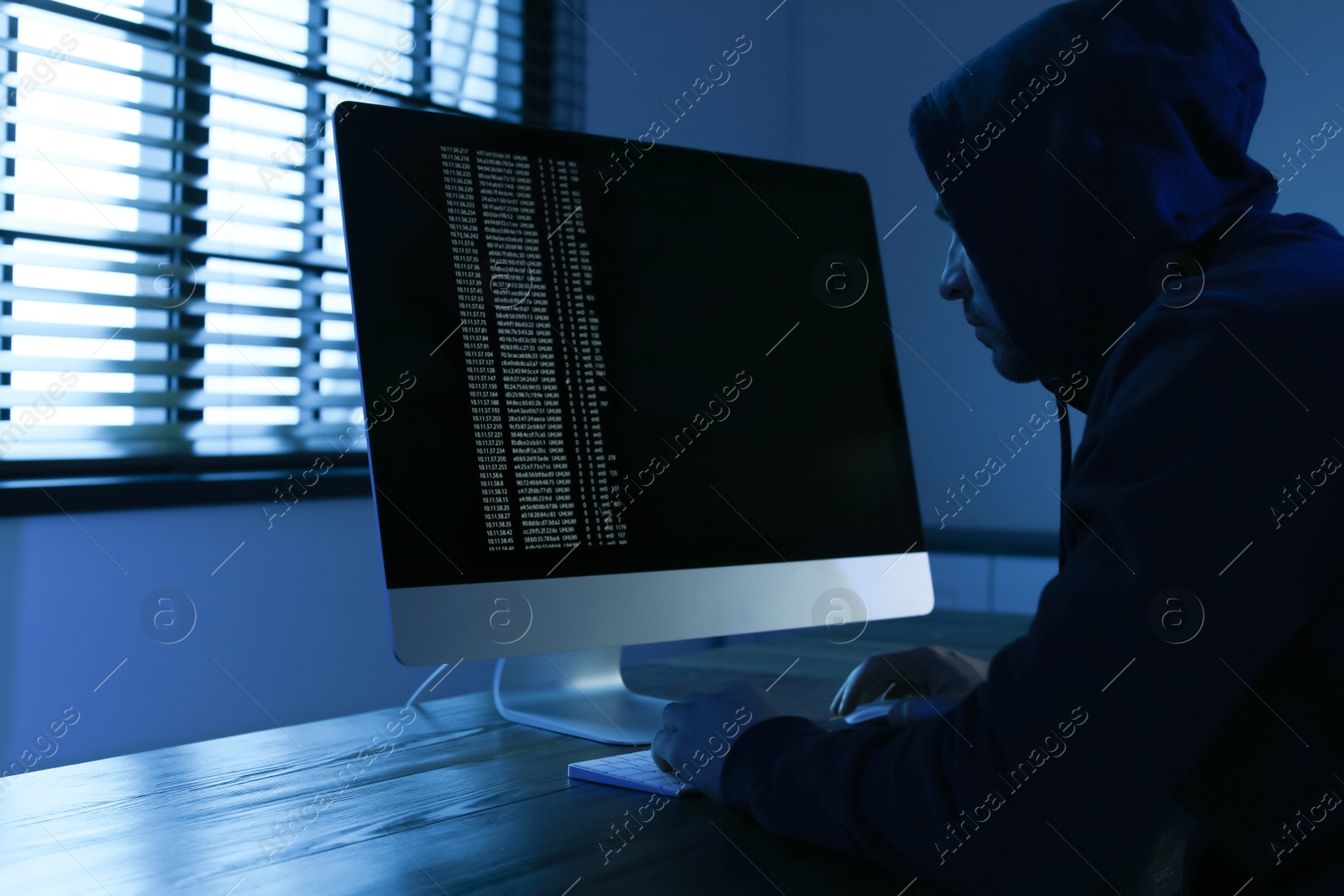 Photo of Man using computer in dark room. Criminal offence