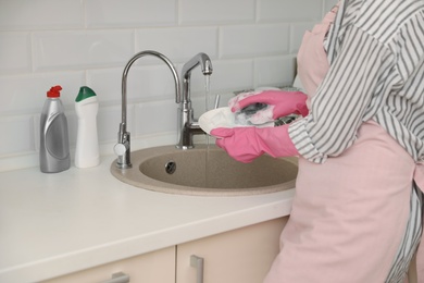 Photo of Woman doing washing up in kitchen sink, closeup view. Cleaning chores