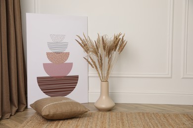 Photo of Fluffy reed plumes and painting near white wall indoors, space for text. Interior elements