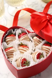 Photo of Heart shaped box with delicious chocolate covered strawberries on white marble table, closeup