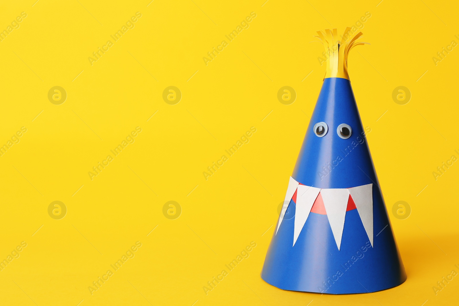 Photo of Funny blue monster on yellow background, space for text. Halloween decoration