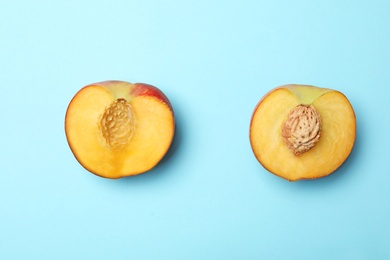 Photo of Halves of sweet juicy peach on light blue background, top view