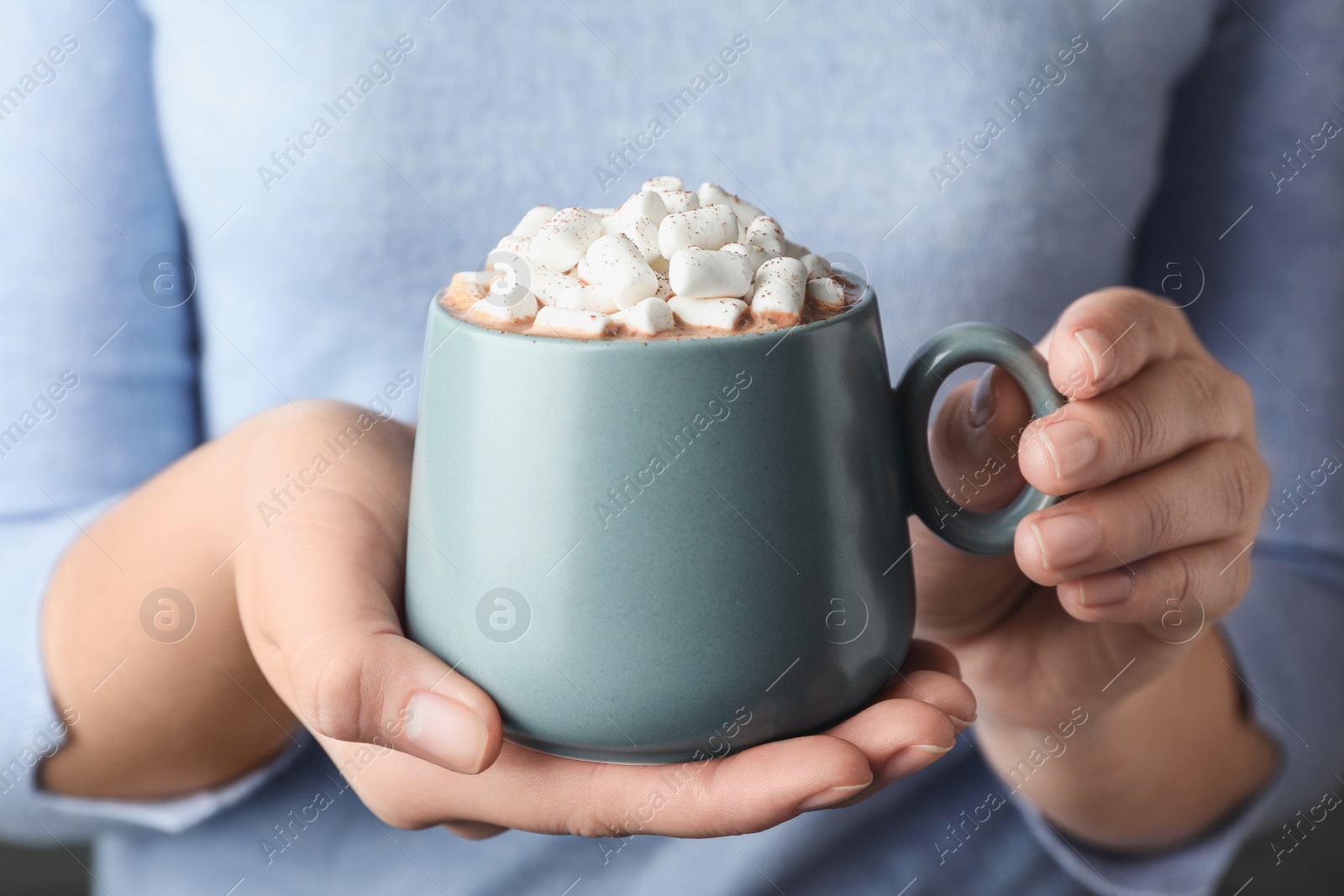 Photo of Woman holding cup of aromatic cocoa with marshmallows, closeup