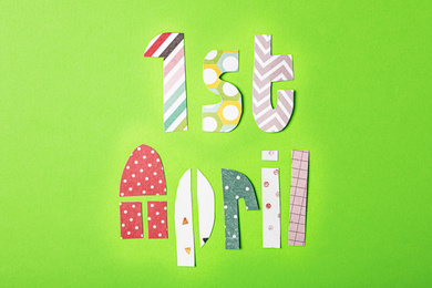 Photo of Phrase 1st APRIL made of paper letters on light green background, flat lay. Fool's Day