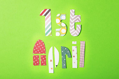 Phrase 1st APRIL made of paper letters on light green background, flat lay. Fool's Day