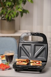 Photo of Modern grill maker with sandwiches and coffee on light grey table indoors