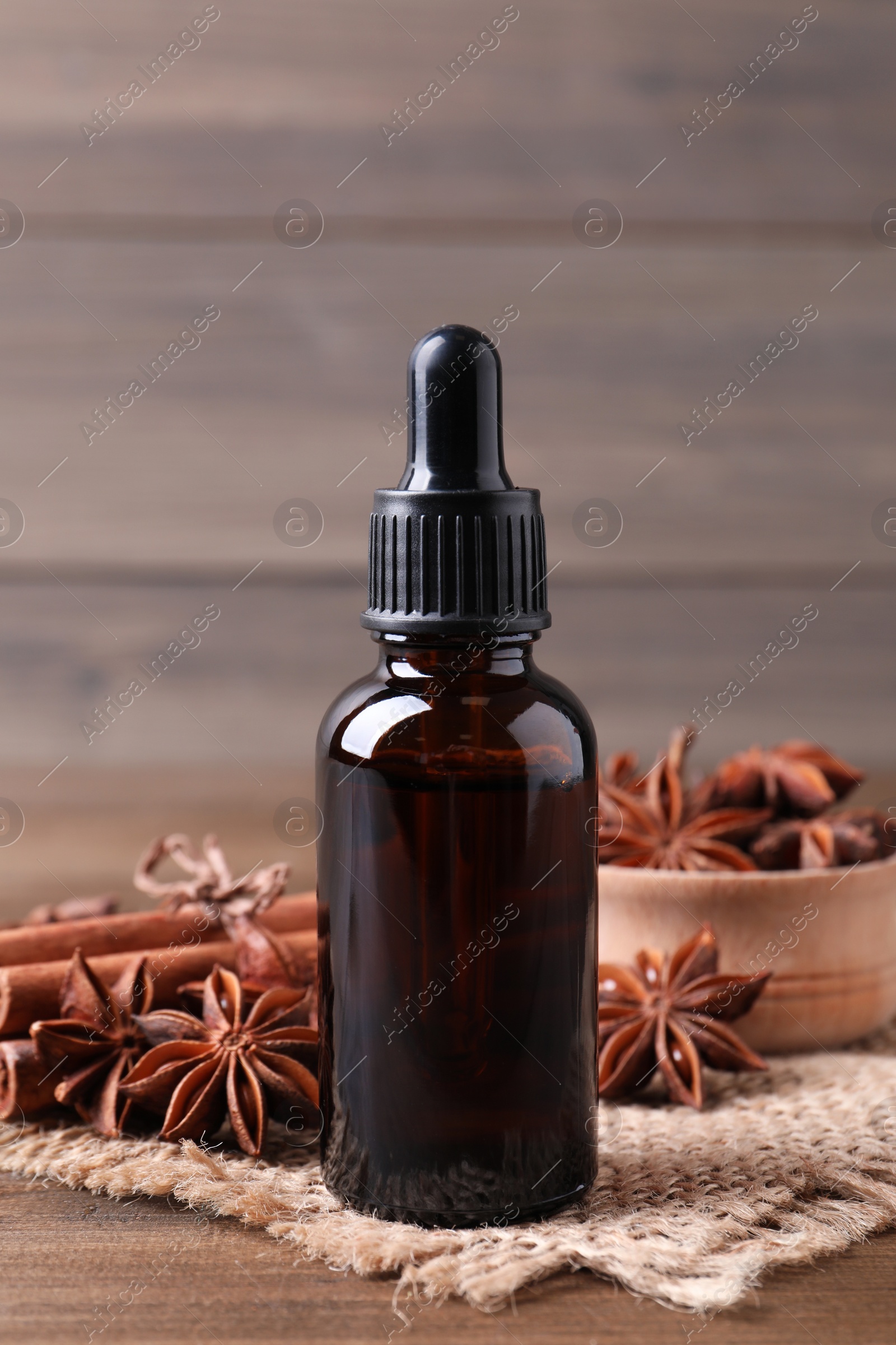 Photo of Anise essential oil and spices on wooden table