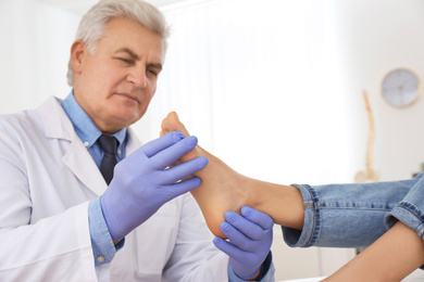 Male orthopedist checking patient's foot in clinic