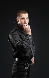 Male security guard using portable radio transmitter on dark background