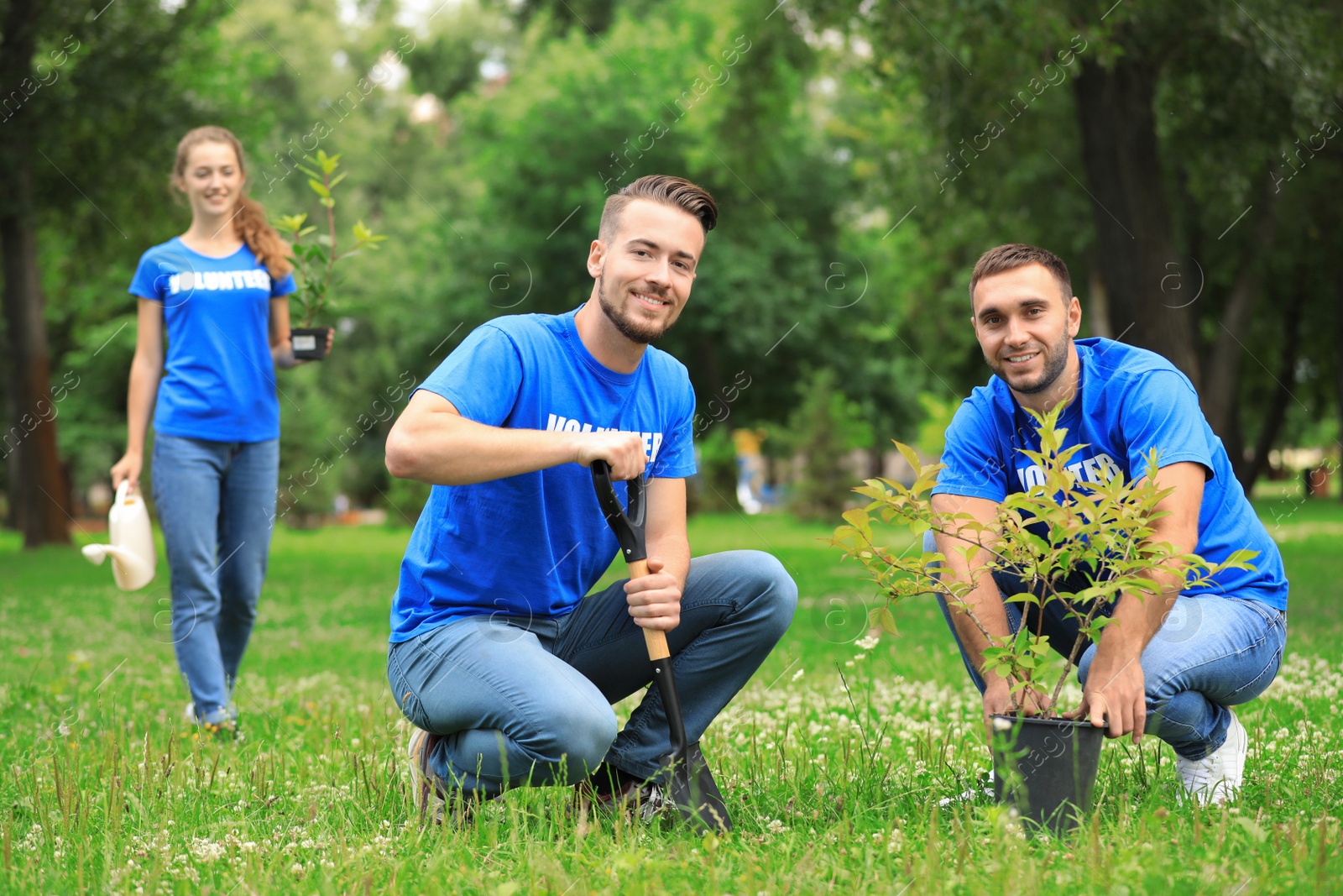 Photo of Young volunteers planting tree in green park. Charity work