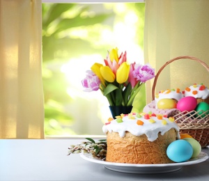 Image of Delicious Easter cakes and painted eggs on light grey table indoors. Space for text