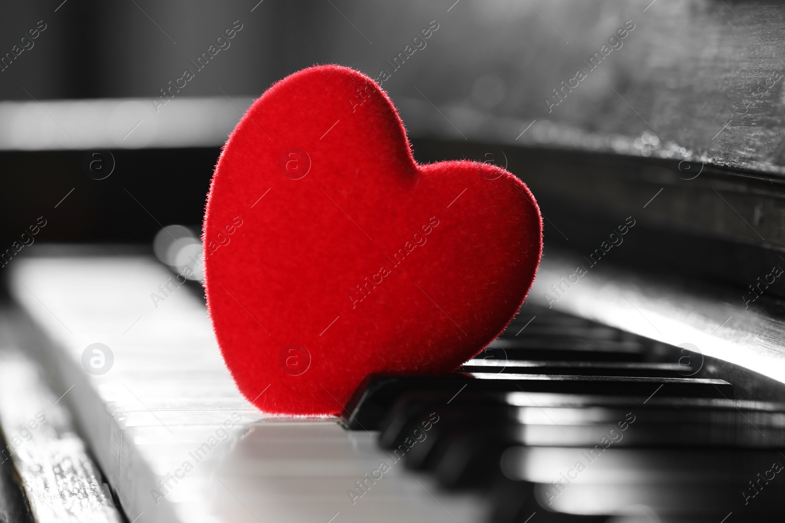 Photo of Small red decorative heart on piano keys, closeup
