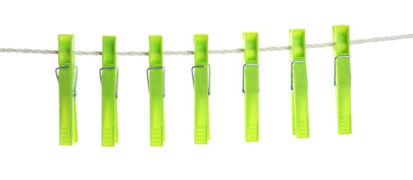 Photo of Bright green plastic clothespins hanging on rope against white background