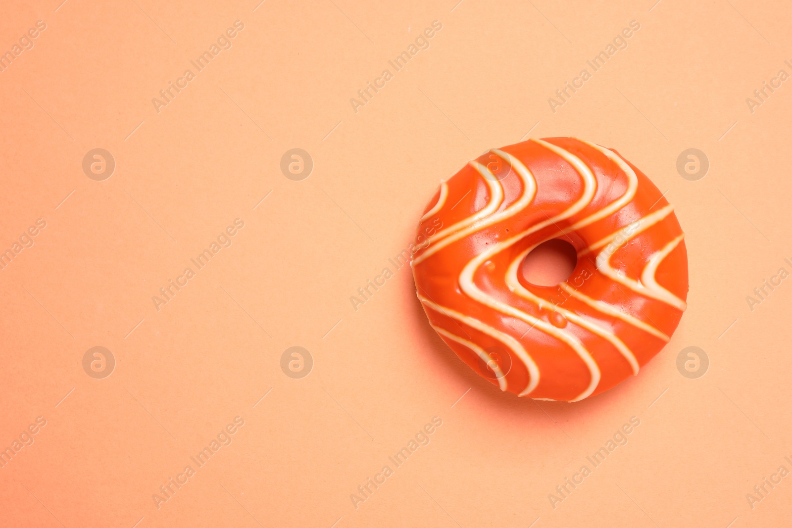 Photo of Delicious glazed donut on orange background, top view. Space for text