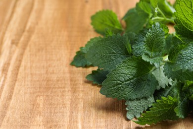 Photo of Fresh lemon balm on wooden table, closeup. Space for text