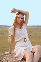 Beautiful hippie woman on hay bale in field
