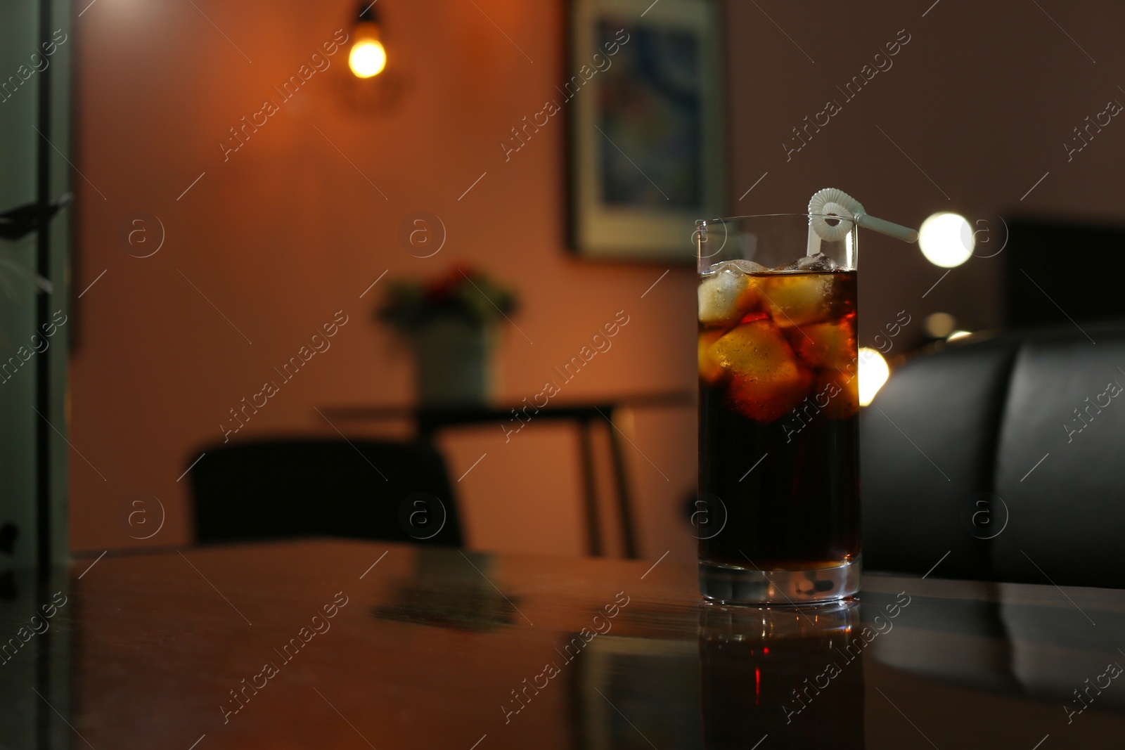 Photo of Glass of cold cola on table in dark room. Space for text
