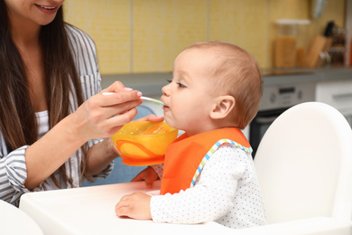 Young mother feeding her little baby at home