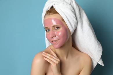 Photo of Young woman with pomegranate face mask on light blue background