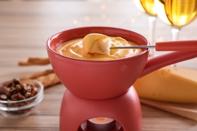 Photo of Pot with delicious cheese fondue and bread on table, closeup