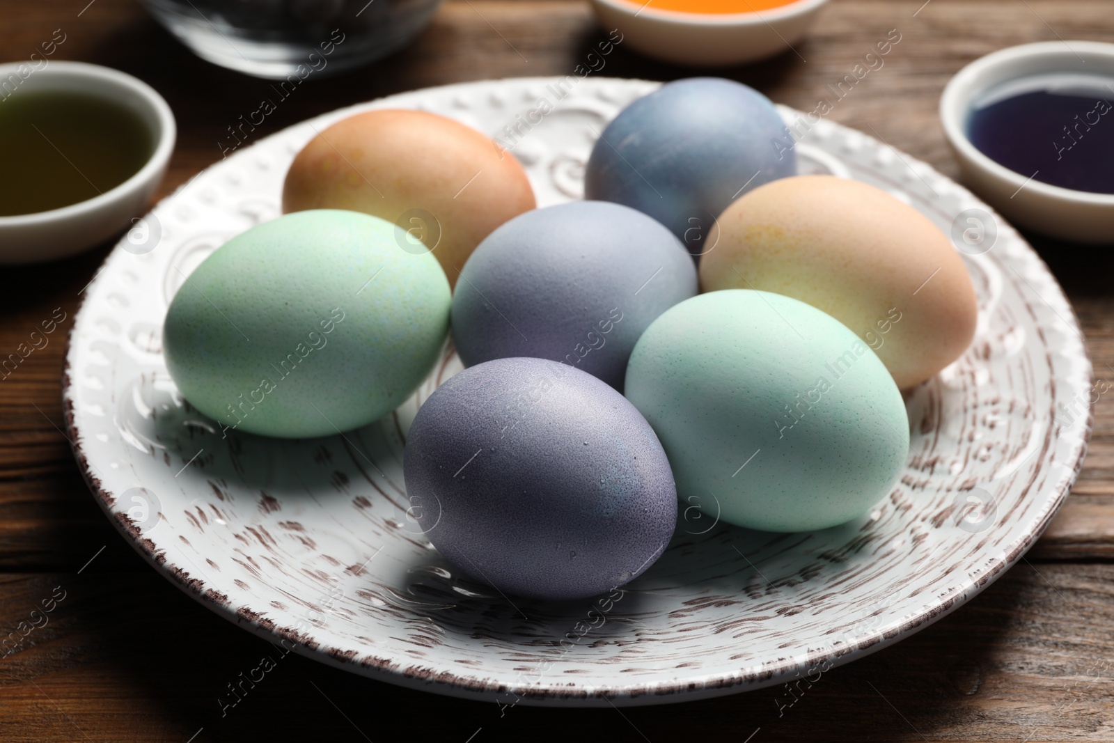 Photo of Easter eggs painted with natural organic dyes on wooden table, closeup