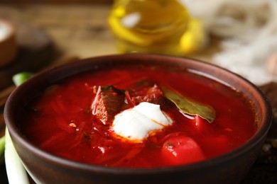 Photo of Clay bowl with Ukrainian borsch on table, closeup