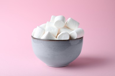 Photo of Delicious puffy marshmallows in bowl on pink background