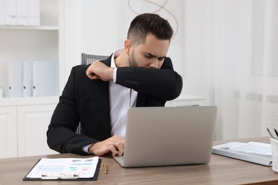 Photo of Sick man coughing at workplace in office