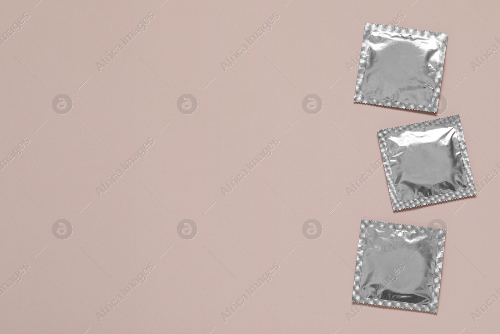 Photo of Condom packages on light pink background, flat lay and space for text. Safe sex