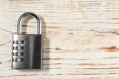 Photo of One steel combination padlock on light wooden table, top view. Space for text