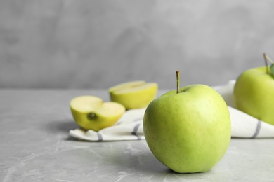 Photo of Fresh ripe green apples on grey stone table against blue background, space for text