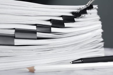 Photo of Stack of documents with binder clips on marble table, closeup
