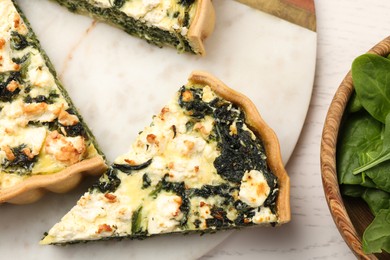 Photo of Pieces of delicious homemade spinach quiche on white table, flat lay