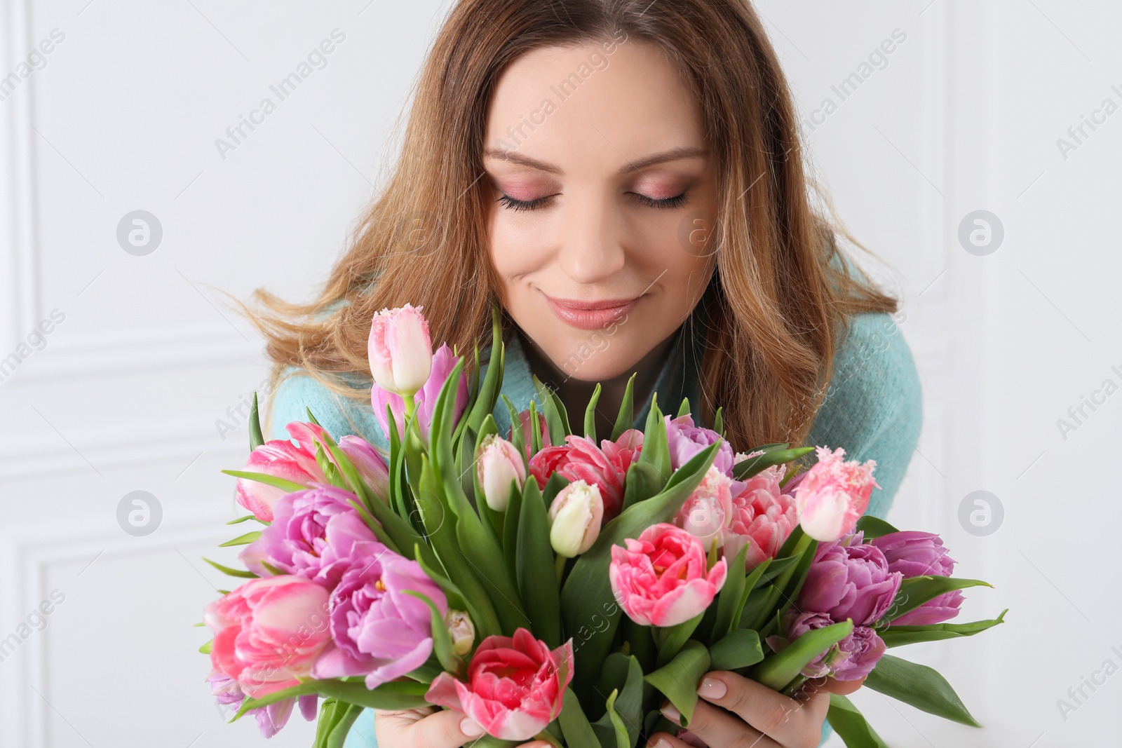 Photo of Young woman with bouquet of beautiful tulips indoors