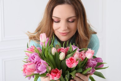 Young woman with bouquet of beautiful tulips indoors