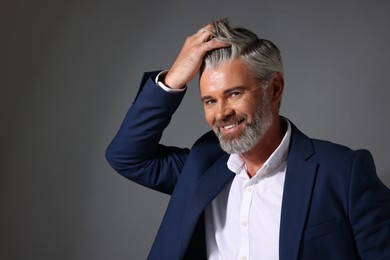 Photo of Portrait of smiling man with beautiful hairstyle on dark grey background