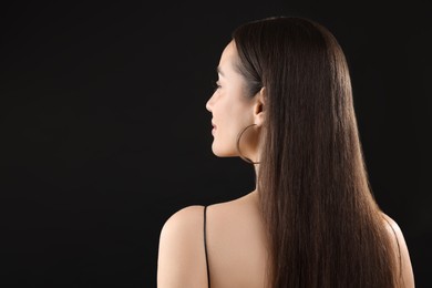 Woman with brunette hair on black background, back view. Space for text