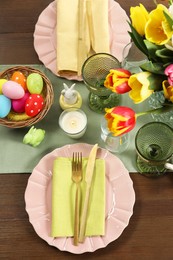 Photo of Easter celebration. Festive table setting with beautiful flowers and painted eggs, flat lay