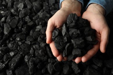 Photo of Man holding coal in hands over pile, above view. Space for text