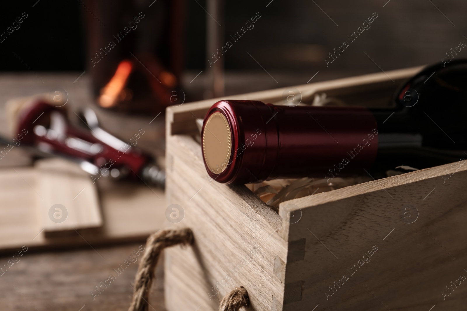 Photo of Open wooden crate with bottle of wine on blurred background