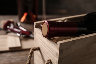 Photo of Open wooden crate with bottle of wine on blurred background